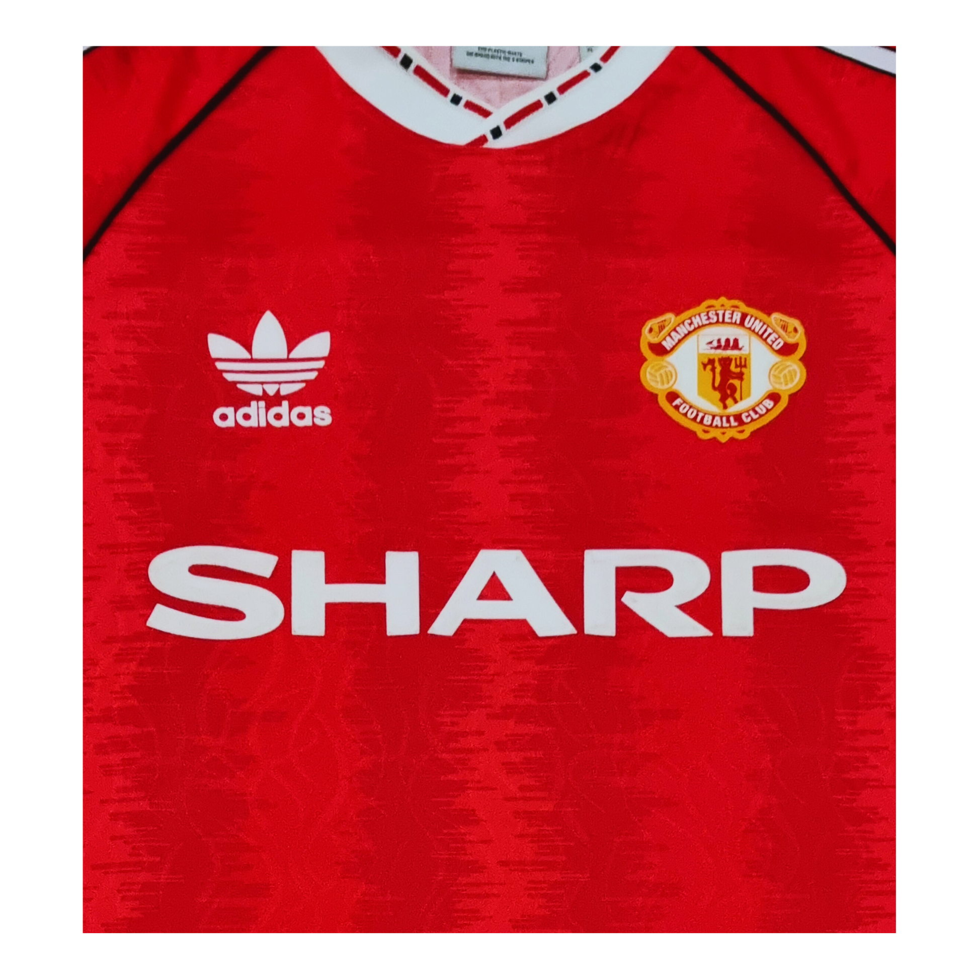 An Adidas Manchester United 1991/92 Home Jersey Re-release with the word sharp on it.