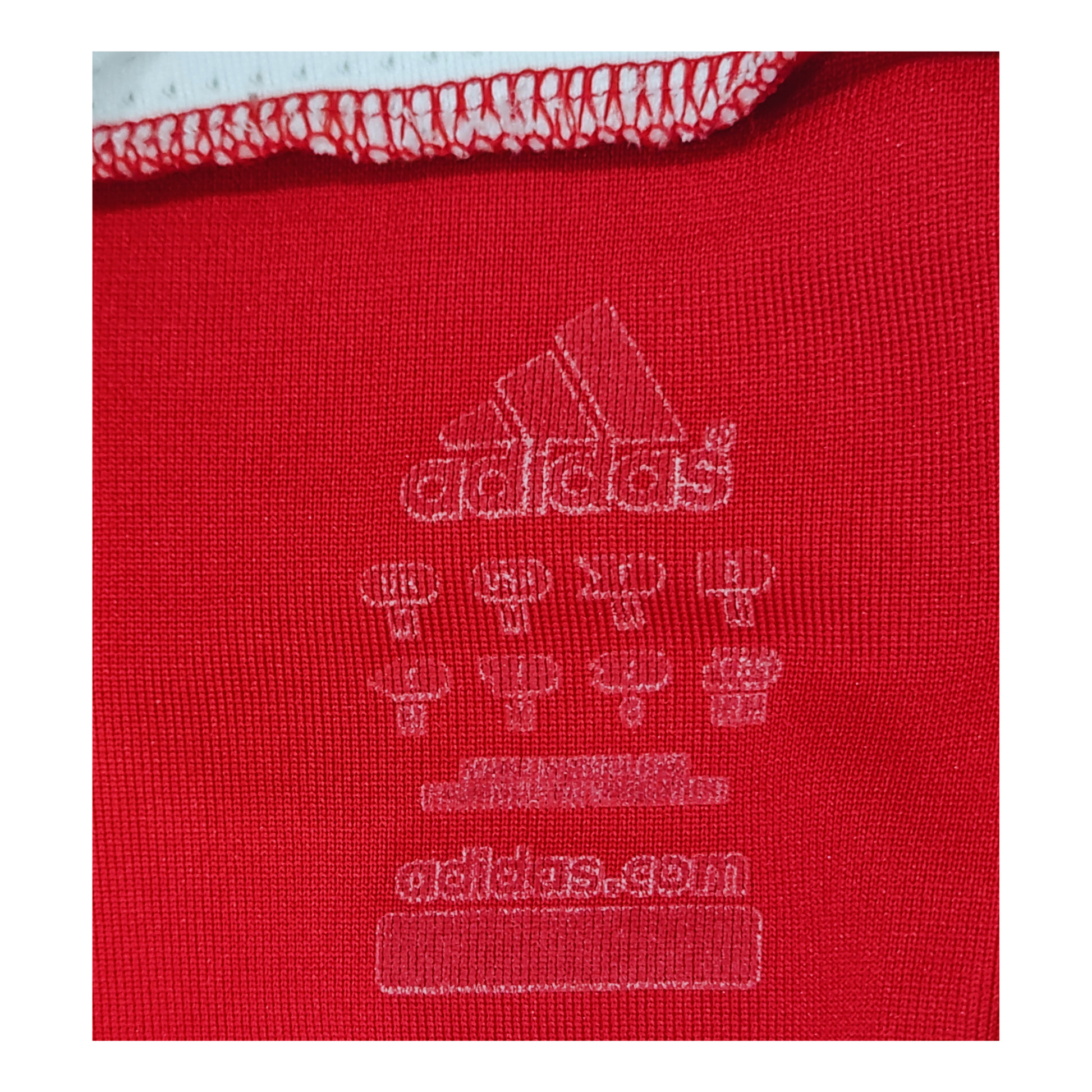 A close up of the Adidas logo on a red Bayern Munich 2007/09 Home Jersey.