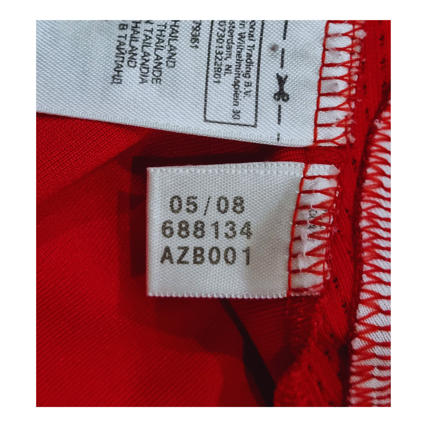 A close-up of a red shirt with a label on it, displaying the Adidas Bayern Munich 2007/09 Home Jersey product code.